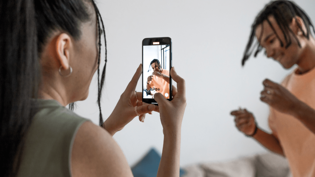 photo of woman recording man dancing. recording videos for tiktok. social media manager creating content recording videos for client